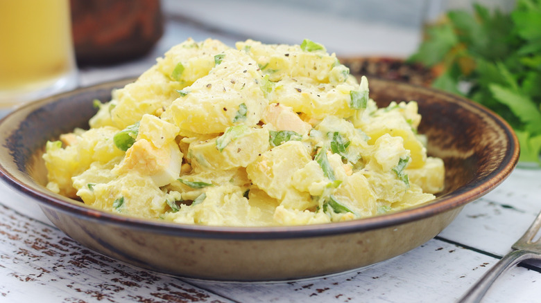 Creamy potato salad in a bowl with herbs on top