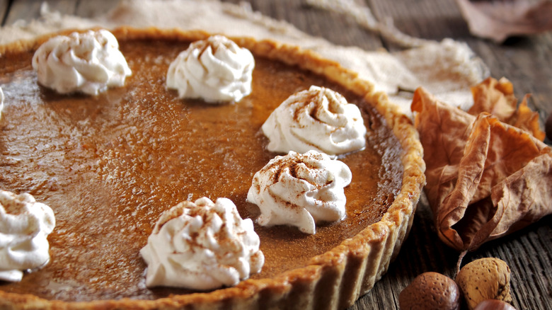 pumpkin pie topped with whippped cream and cinnamon spice