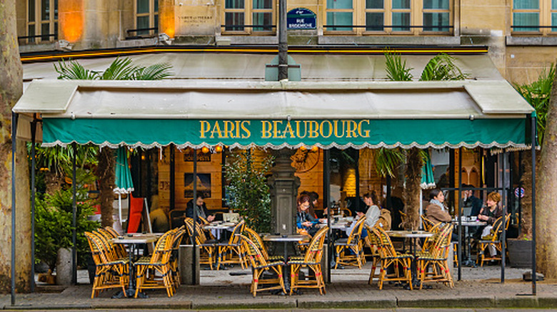The exterior of a French cafe, with a teal awning that reads "Paris Beaubourg"