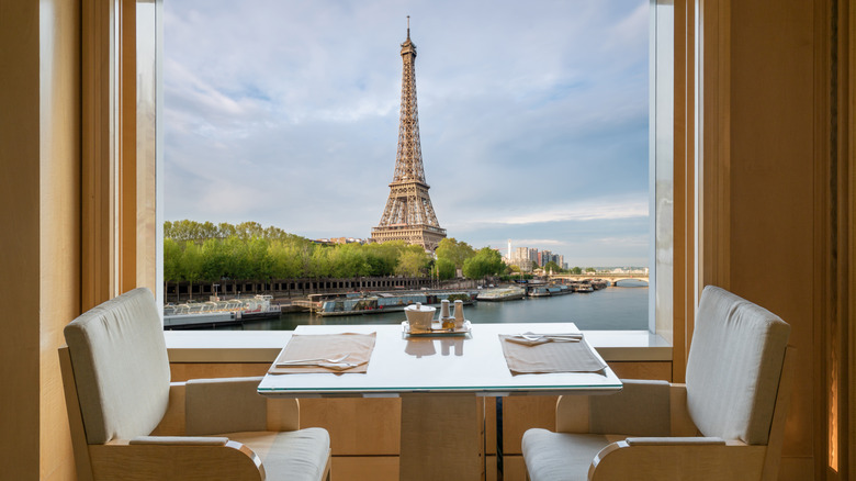 A table in a restaurant next to a window that has a full view of the Eiffel Tower