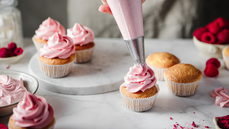 piping frosting on cupcakes