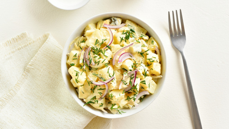 Bowl of potato salad on a white surface.