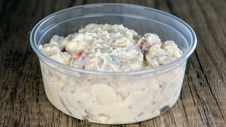 Supermarket-made potato salad in a plastic container.