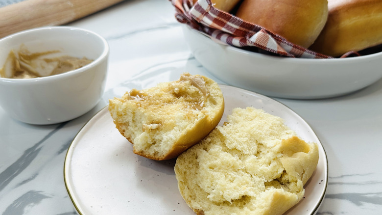 split, buttered bread roll on a white plate