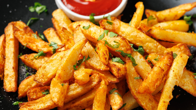 Crispy french fries garnished with parsley and served with ketchup