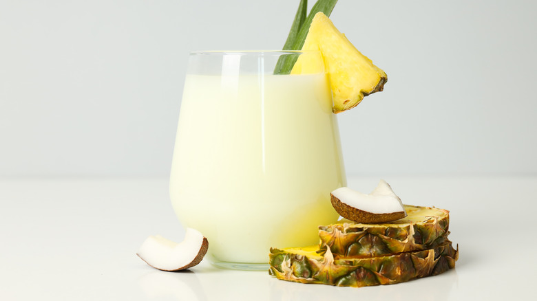 piña colada alongside pieces of pineapple and coconut