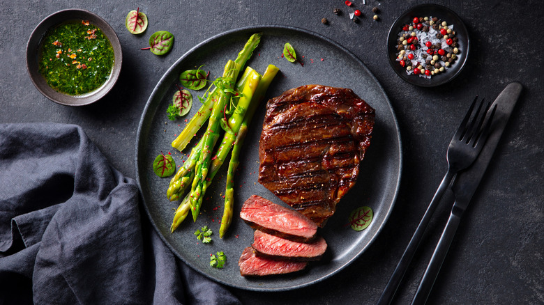 Sliced rare sirloin steak on a gray plate with asparagus spears