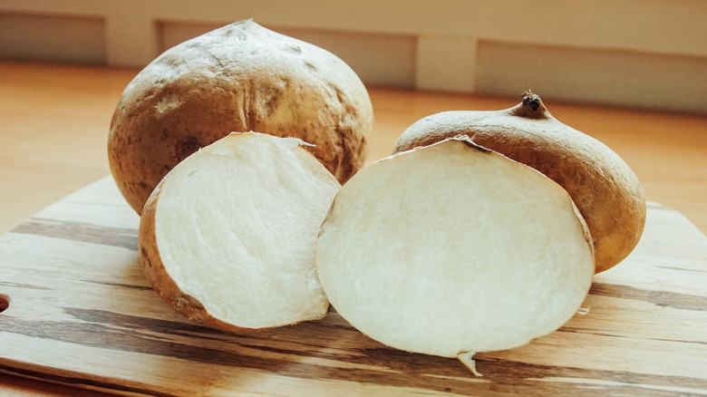 Whole and halved jicama on a cutting board