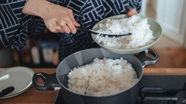hands scooping freshly cooked rice into a bowl
