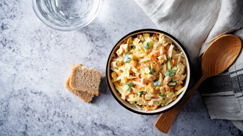 A bowl of coleslaw with diced cucumbers.