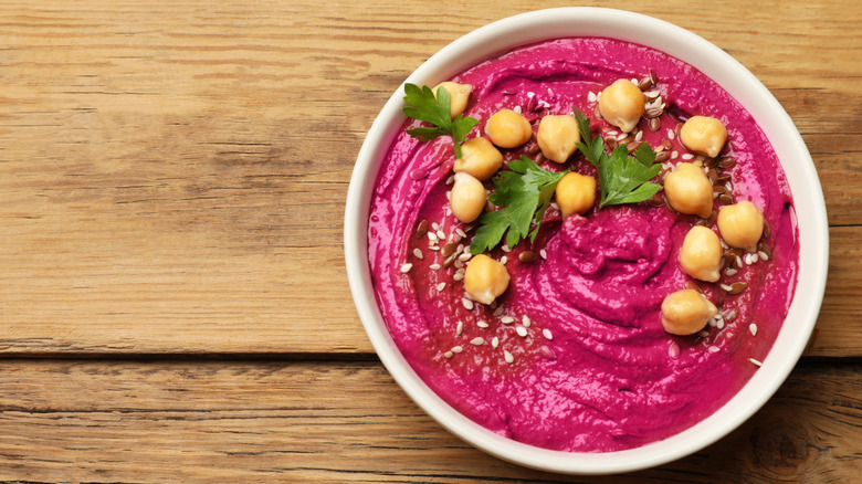 Beet hummus in a bowl on a wooden surface