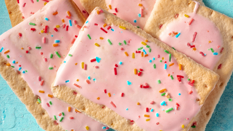 Pop Tarts with strawberry frosting and rainbow sprinkles on a cooling rack.