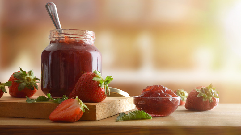 A jar of strawberry jam with a spoon in it