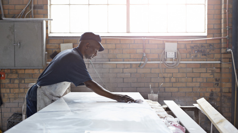 A person polishing a slab of marble in a workshop