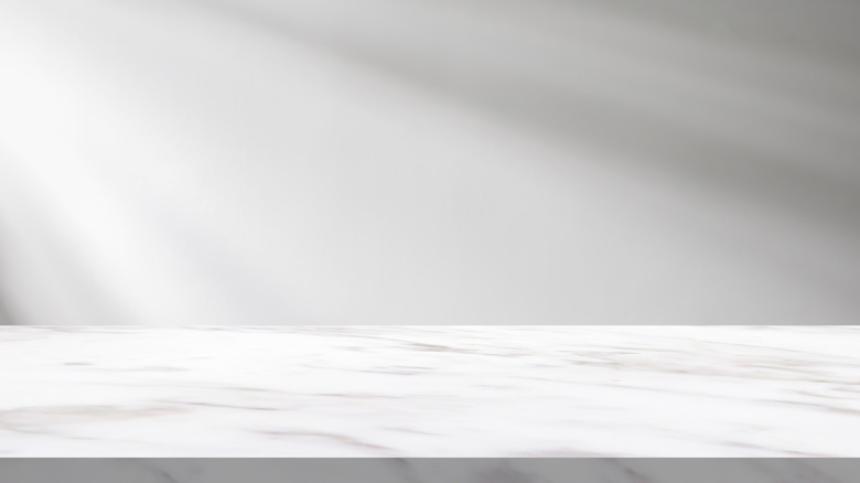 A white marble surface with a white background and natural light slanting in on the left
