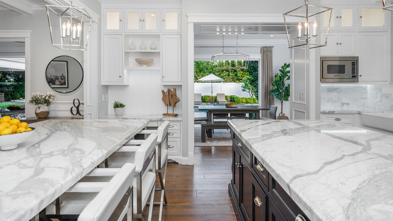 Marble countertops and a large marble island in a modern kitchen painted white