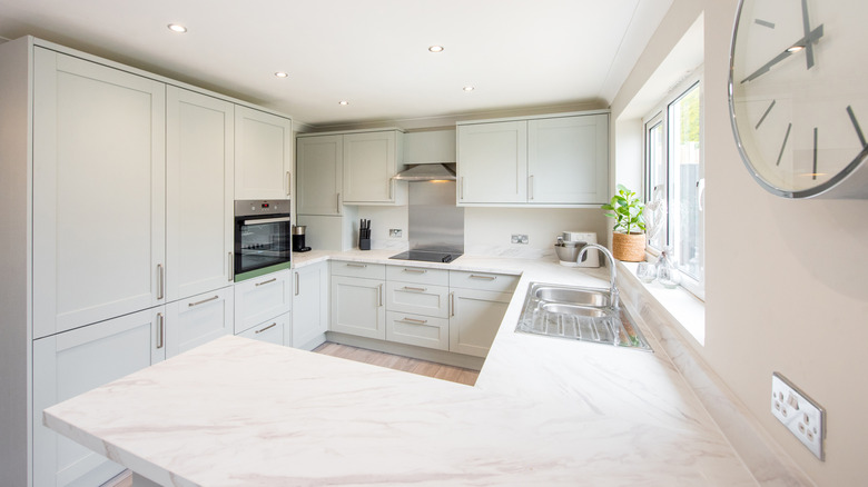 A white marble counter in a modern kitchen with white cabinets
