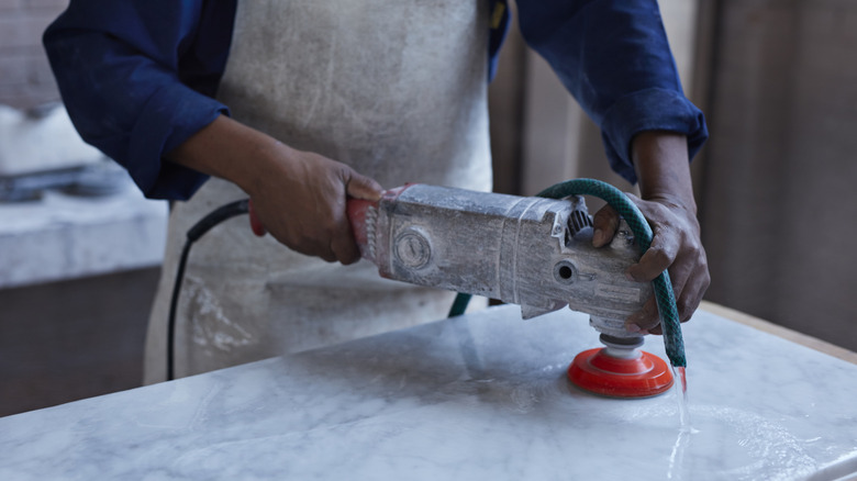 A professional using a power tool to work on a marble slab