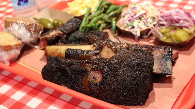 Brisket on a tray with sides, including cornbread, coleslaw, and green beans.