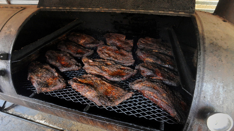 Several brisket roasts cooking in a smoker.