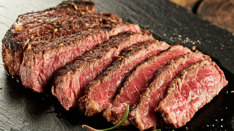 Sliced, juicy steak arranged on a black surface