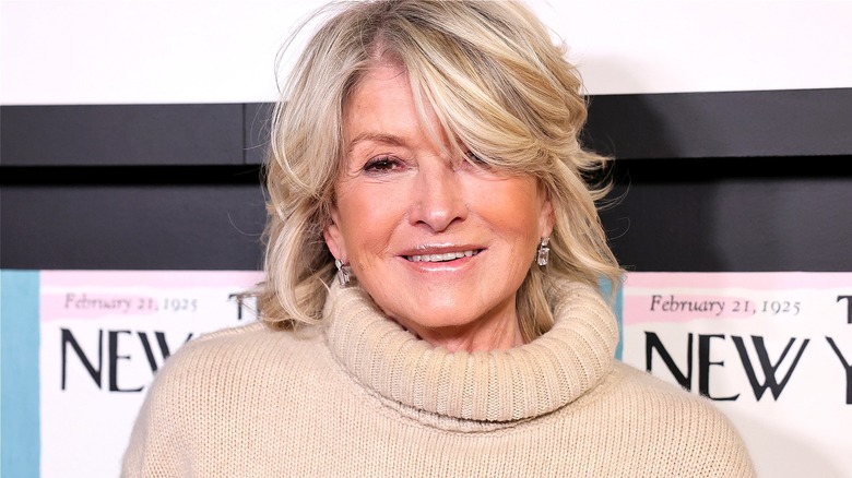 Martha Stewart smiling in a taupe-colored fold-over turtleneck sweater