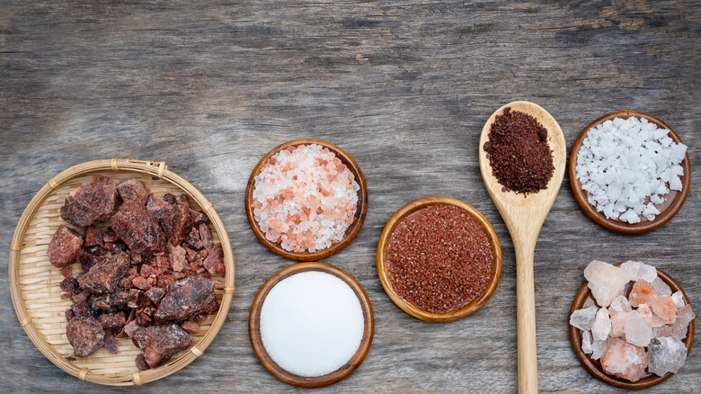 Different types of salt in wooden bowls and a wooden spoon