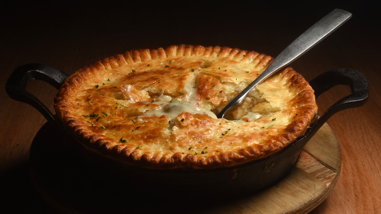 Chicken pot pie with a spoon in it on a wooden background