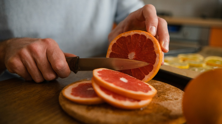 A person cutting slices of grapefruit