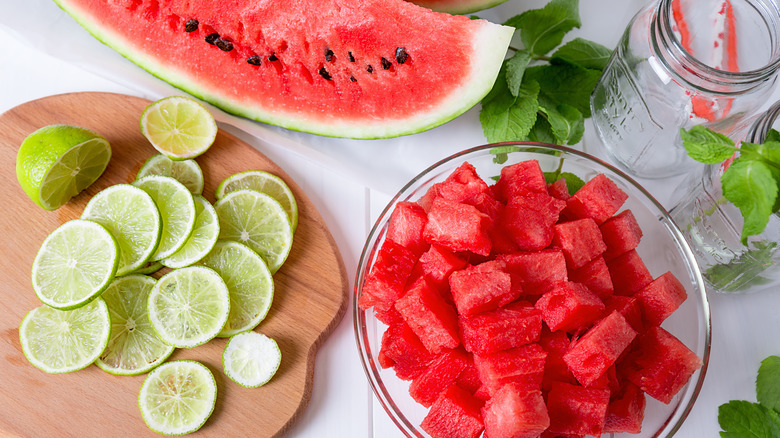 Cut up watermelon in a bowl and limes on a cutting board
