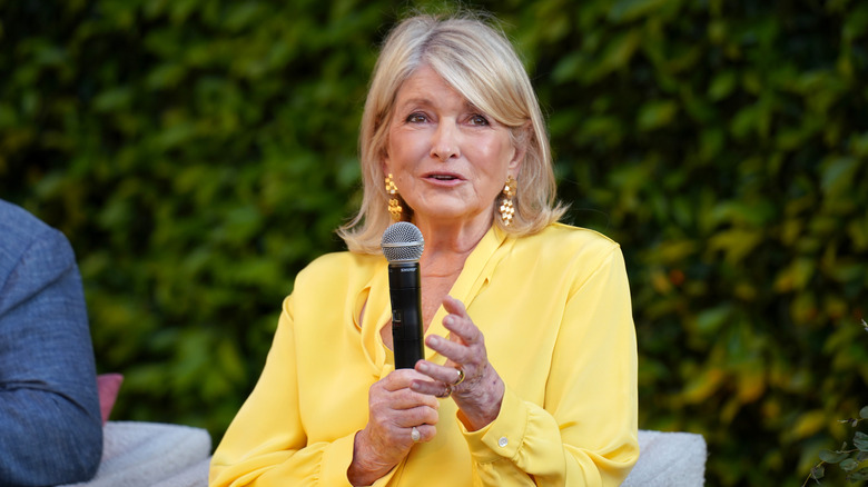 Martha Stewart wearing a yellow blouse speaking into a microphone