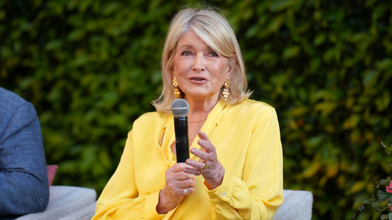 Celebrity chef Martha Stewart speaking at an outdoor industry event with a microphone.