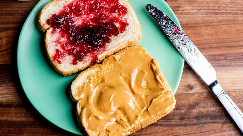 PB&J sandwich on a green plate, knife beside plate