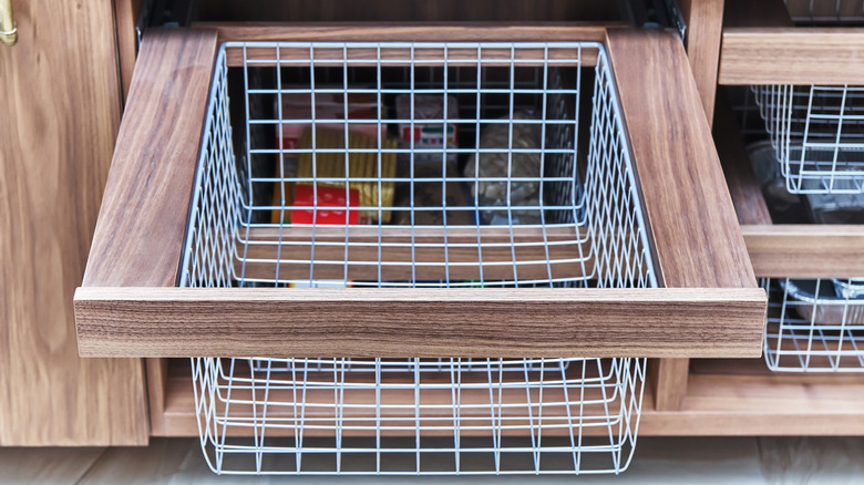 A wire mesh drawer opens out from a pantry.