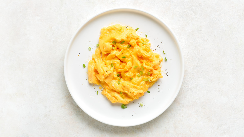 Scrambled eggs with green onions on a white plate