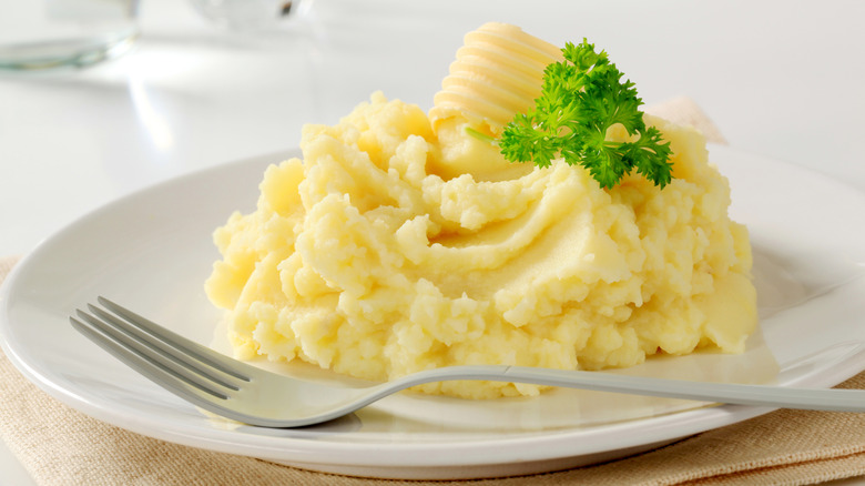 A plate of mashed potatoes with a fork.