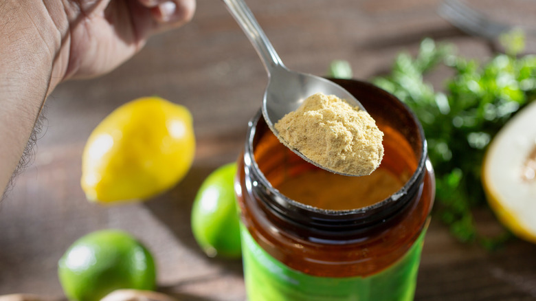 Person holding a spoon scooping chicken bouillon out of a jar