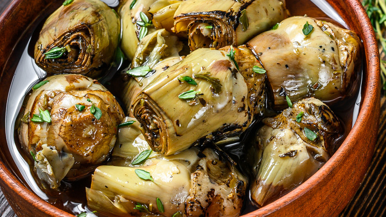 Artichoke hearts pickled in olive oil. wooden background. Top view. Copy space