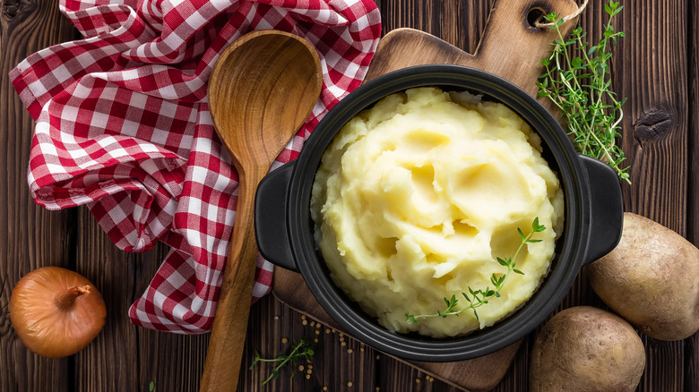 Bowl of mashed potatoes on wooden table with spoon