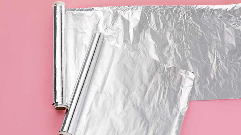 two rolls of shiny aluminum foil against pink background