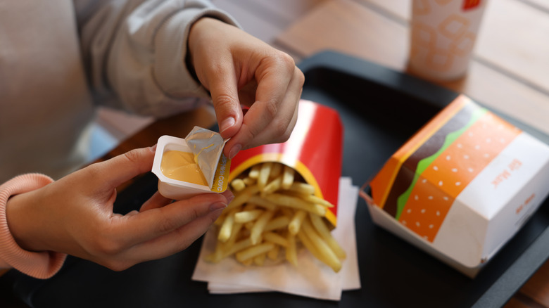 Person opening McDonald's dipping sauce for fries and a Big Mac
