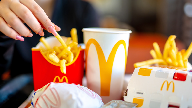 Hand grabbing fry from McDonald's meal.