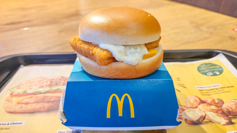 McDonald's Filet-O-Fish with tartar sauce sitting on top of its blue box on a tray