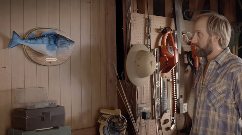 A man stares at a plastic fish on the wall