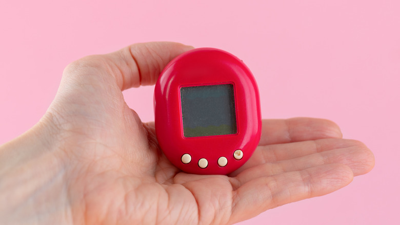 A person holding a red Tamagotchi toy