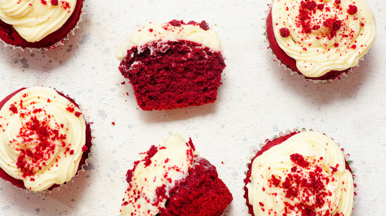 Several red velvet cupcakes and one is cut in half
