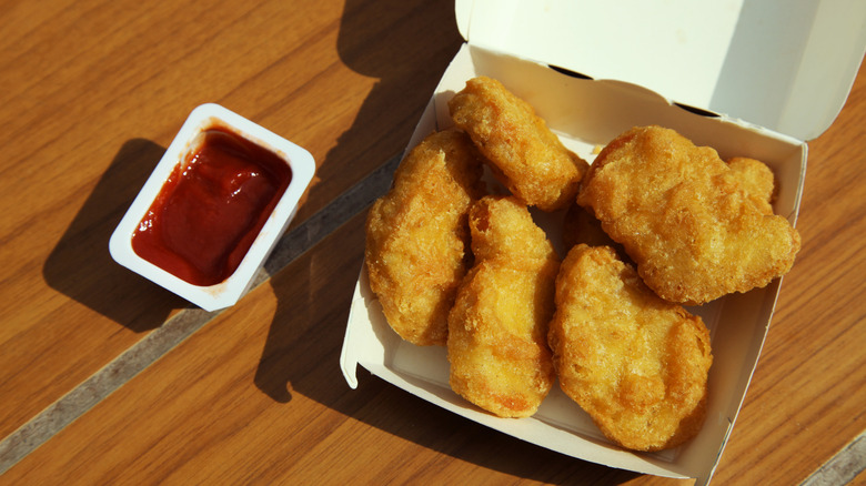 box of McNuggets and ketchup on brown wooden table