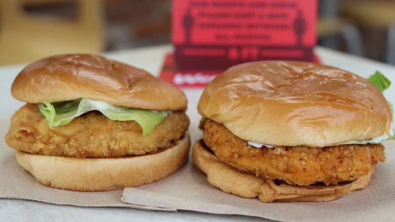 Two fast food fried chicken sandwiches sitting next to each other on a tray.