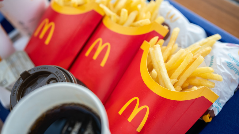 three boxes of McDonald's french fries on a tray with drinks