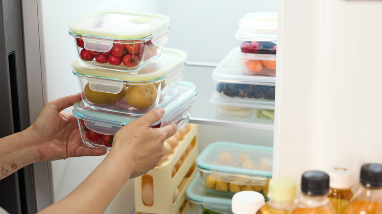 A person is is putting meal prepped containers into the fridge.